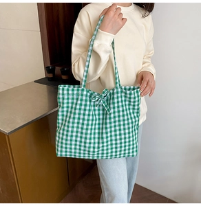 Detail of green plaid canvas tote bag with a decorative bow and matching shoulder strap