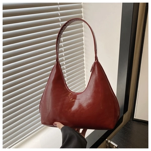 Close-up of deep red glossy patent leather hobo bag with embossed fashion lettering