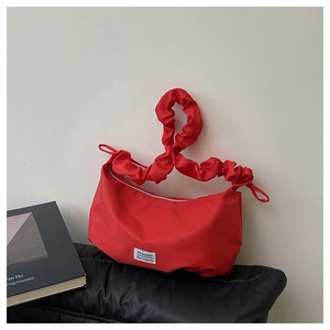 Détail d'un sac à main rouge en nylon avec étiquette FASHION et poignée à volants