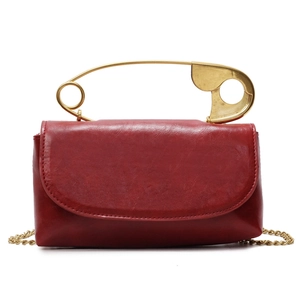 Red wax-finish leather handbag with large gold safety pin handle and chain strap