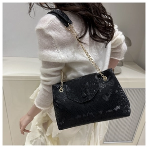 Détail du sac à bandoulière noir effet serpent avec élégante chaîne dorée