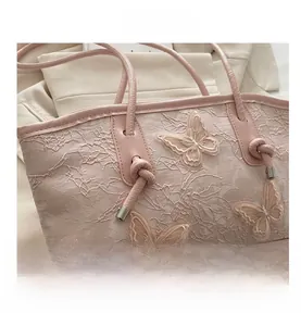 Detail of pink lace handbag featuring 3D butterfly embroidery and rope handle