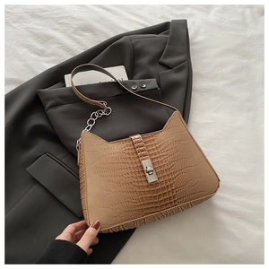 Close-up of brown crocodile texture handbag with silver twist lock on a grey suit