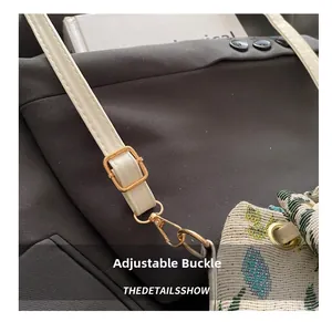 Detail of adjustable gold buckle and cream faux leather strap on tapestry woven bag