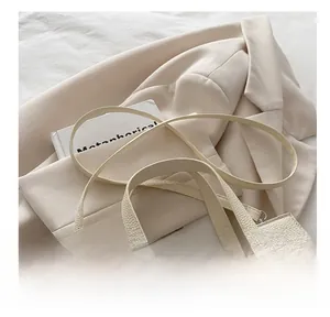 Detail of off-white lychee grain leather handbag with silver lock and detachable strap