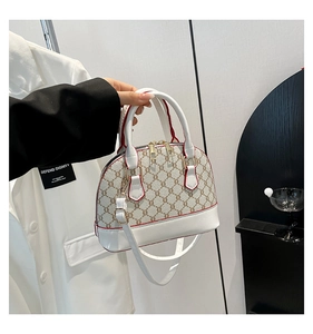 Detail of a dome bag featuring beige monogram canvas and white leather trim accents