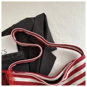 Detailed macro view of red and white striped knit bag strap with red lace embroidery