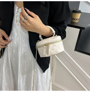 Detail of cream quilted mini box bag with gold chain strap and dual zipper closure