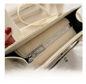Close-up of smooth silver zipper and premium lychee texture on off-white handbag