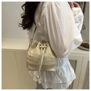 Detail of beige straw bucket bag featuring herringbone weave and leather drawstring closure