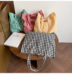 Detailed view of four colorful checkered canvas tote bags on a wooden table in soft light