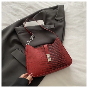 Close-up of deep red crocodile embossed hobo bag with silver turn-lock and chain strap