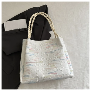 Top view of white quilted tote bag with colorful wavy lines and woven handles