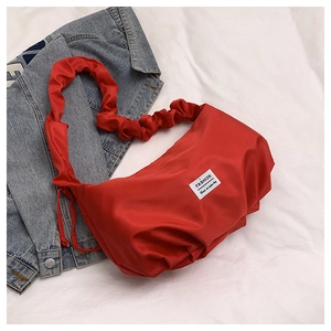 Detail of red ruched nylon shoulder bag with puff texture and white brand label
