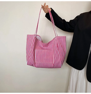 Detail of red and white striped canvas tote bag with front pocket and long handle straps