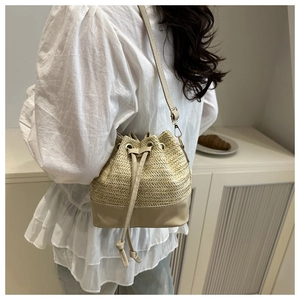 Detail view of woven bucket bag with beige straw texture and light brown leather trim
