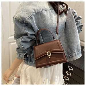 Brown rectangular leather crossbody bag with golden hardware shown on a model