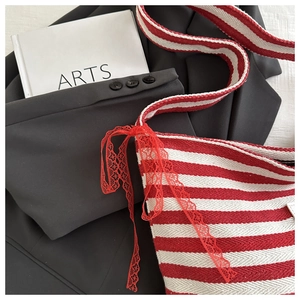Detail of red and white striped knit tote bag featuring a red lace bow decoration