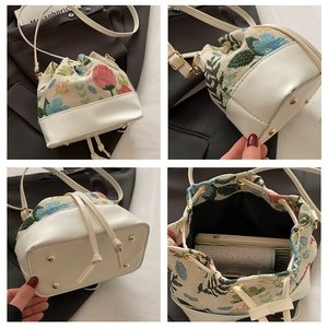 Detail of floral tapestry bucket bag with drawstring closure and metal bottom studs