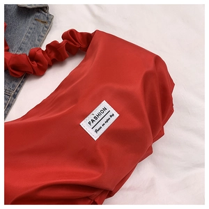 Gros plan du sac en nylon plissé rouge vif avec étiquette de mode sur fond de tissu