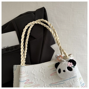 Detail of white embossed tote bag with colorful wave embroidery and a cute panda charm