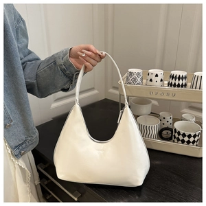 Close-up of minimalist white half-moon shoulder bag with sleek leather texture and embossed detail