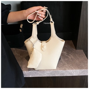 Detail of cream white textured bucket bag with small pouch on marble surface