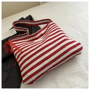 Close-up of red and white striped canvas bag featuring a side lace bow and fabric patch