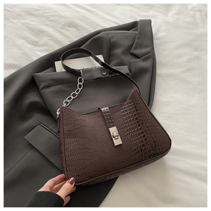 Detail of dark brown crocodile embossed shoulder bag with silver chain and twist lock