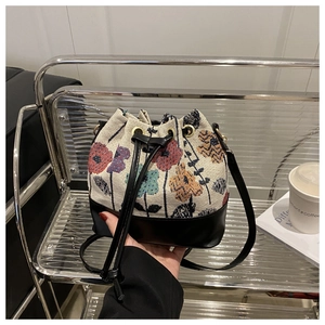 Close-up of floral fabric and black leather bucket bag with drawstring closure