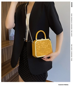 Close-up of yellow octagonal box bag featuring floral relief and gold metal lock