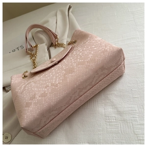 Détail de la texture serpent rose pâle et de la bandoulière en chaîne dorée du sac