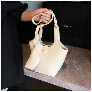 Detail of cream bucket bag in lychee leather featuring a matching mini zip pouch attachment