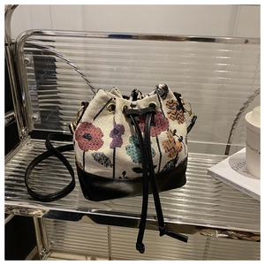 Close-up of floral tapestry fabric and black leather on drawstring bucket bag