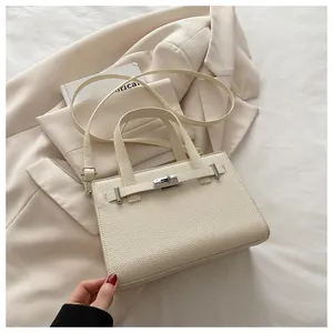 Close-up of ivory lychee leather handbag featuring silver twist lock and strap detailing