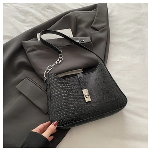 Close-up of crocodile pattern leather bag with silver chain and metal turn lock