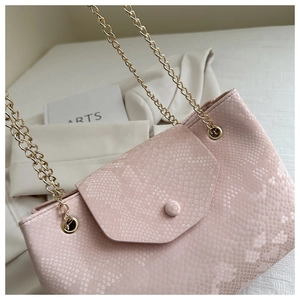 Gros plan du sac rose à motif serpent avec d'élégantes chaînes en métal doré