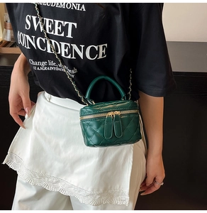 Close-up of dark green quilted mini vanity bag with woven chain strap on a model