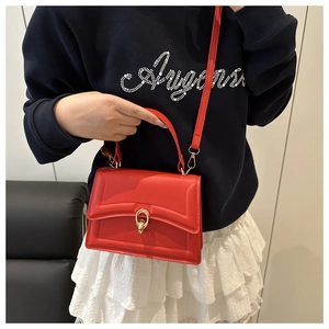 Detail view of red leather crossbody bag with gold ring buckle and adjustable strap