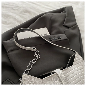 Detail of white crocodile-embossed leather bag with chunky silver chain decoration