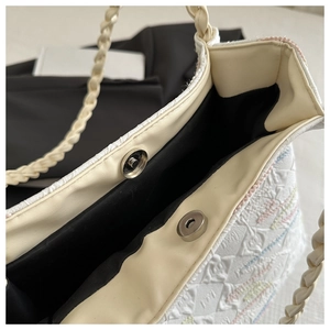 Close-up of metal magnetic buckle and black lining on textured white bucket bag