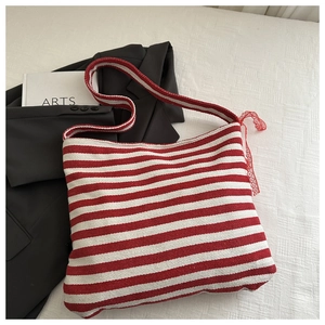 Detail of red and white striped knit tote bag with decorative side lace bow and soft texture