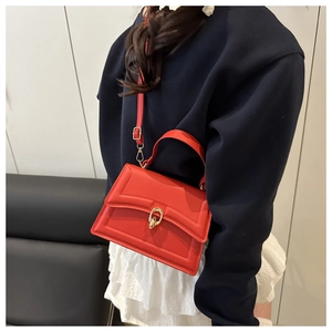 Side view of woman carrying a red leather crossbody bag with golden U-shaped lock