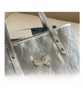 Detail of silver metallic tote bag showing crinkled texture and liquid metal butterfly charm