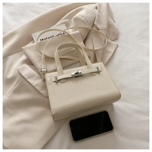 Detail of off-white lychee grain leather handbag with metal turn-lock and elegant strap