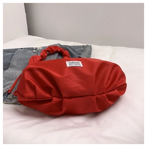 Détail du sac fourre-tout en nylon plissé rouge avec étiquette mode sur denim