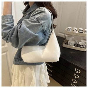 Close-up of minimalist white PU leather hobo bag with subtle fashion lettering and metal zipper