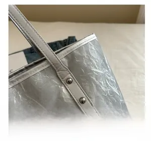 Detail of silver tote bag with crinkled metallic texture and bunny logo hardware