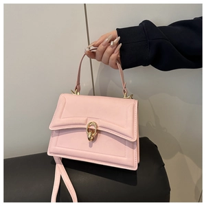 Detail of pink crossbody bag featuring golden double ring buckle and leather texture
