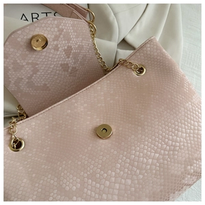 Détail du sac en similicuir rose clair avec texture serpent et chaîne dorée